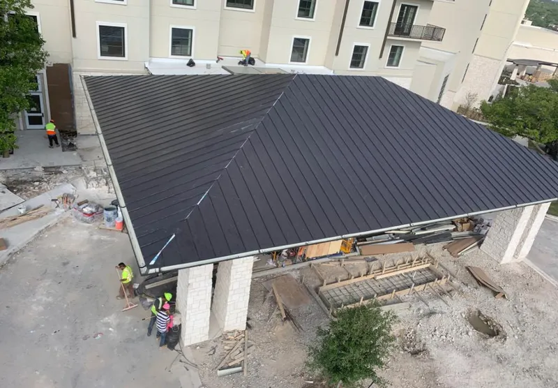 Metal roofing installation team working on a commercial building in Irondequoit